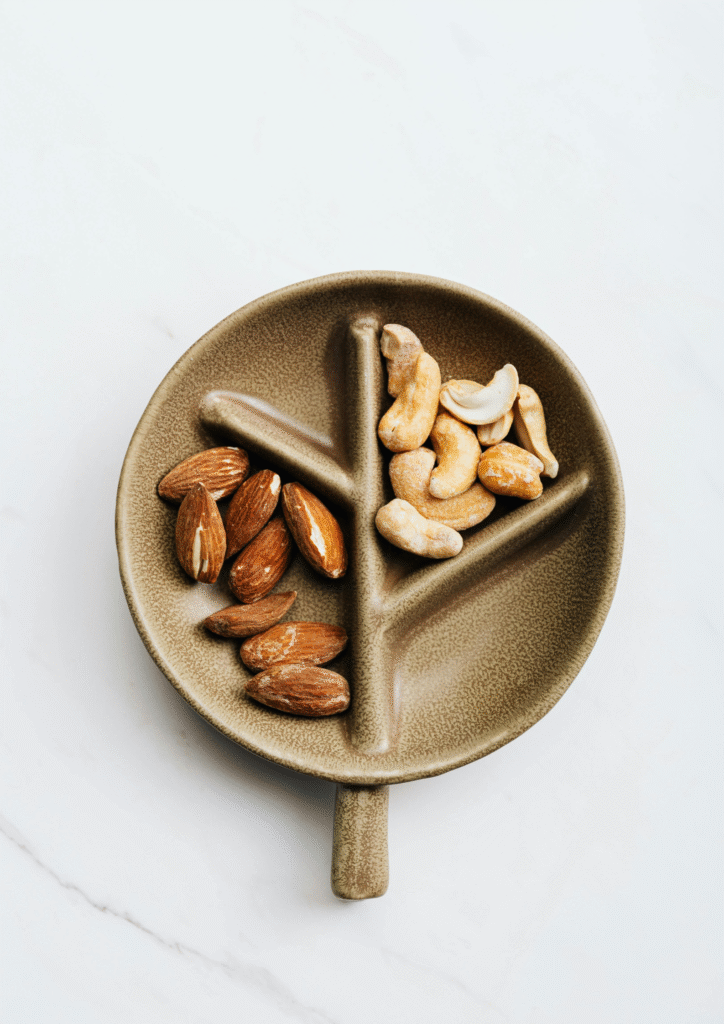 A picture of a compartment plate having cashews and almonds in separate compartments.